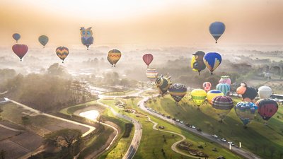 Balloons ascending into the sky over Singha Park's rolling hills and plantations. Photo by: Phudinan Singkhamfu