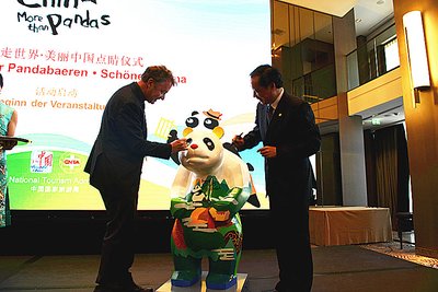 Li Jinzao, chairman of the China National Tourism Administration, and Jochen Szech, president of the Alliance of Independent Travel Traders, added the finishing touches to the eyes of the panda serving as the mascot to the event.