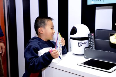 铂涛旅行展厅内，小朋友正在跟智能客房机器人小白聊天
