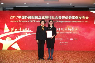 中国外商投资企业协会副会长李玲（左）向荷兰皇家菲仕兰中国企业社会总监王雪彤（右）颁发奖牌
