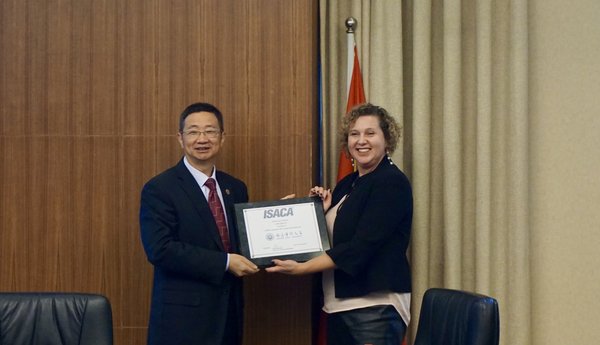 南京审计大学副校长张金城教授接过美国ISACA全球公共事务高级副总裁Tara Wisniewski女士代表ISACA送上的纪念品，共同庆祝双方成功合作一周年