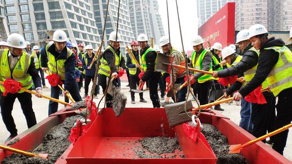 T1塔楼封顶仪式活动现场，重庆来福士项目开发总经理吴焕忠（左4）与中建八局建设者将最后一方混凝土送入楼顶