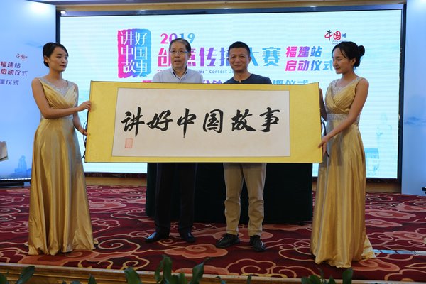 图为中国外文局副局长方正辉（图中左）为“讲好中国故事”书法卷轴盖印。