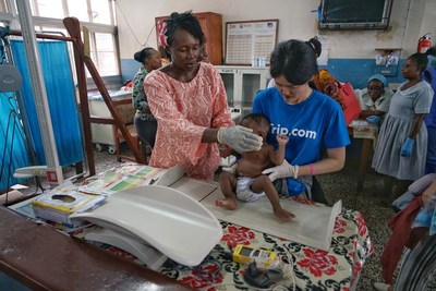 Trip.com volunteer helps to measure the nutrition level of a child at a local clinic.