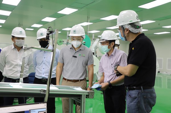 Suphachai Chearavanont (center), CEO of C.P. Group, visiting the production line inside the surgical face mask factory