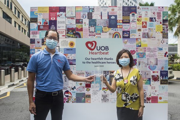 (From left) Mr Eric Lim, Head of Group Finance, UOB and Loh Shu Ching, Executive Director, Division of Central Health showing their appreciation to frontline healthcare workers at Tan Tock Seng Hospital with the UOB Tribute Canvas.