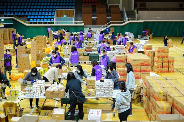图中志愿者正在将用捐款采购到的物资装入纸箱，这些“爱心包”会派发给顺天市的贫困人群。（图片由顺天市政厅提供，不可出售）