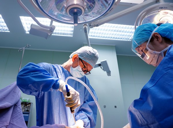 Dr. Ivan Puah, Medical Director of Amaris B. Clinic, assisted by a surgically-trained staff nurse, while he is performing fat removal in an operating theatre during a gynecomastia surgery in Singapore.