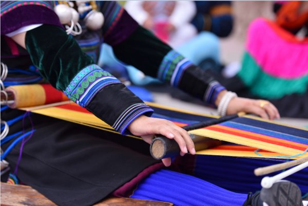 彝族绣娘用腰机织布机来织造土布
