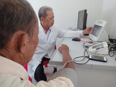 图为澄迈县罗驿村乡村医生李受兴（左）正在使用熙康益体机为村民测量血压