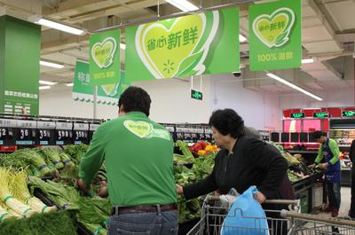 北京沃尔玛商场宣武门店员工正在整理蔬菜并进行品质检查，确保顾客买到优质新鲜的生鲜商品