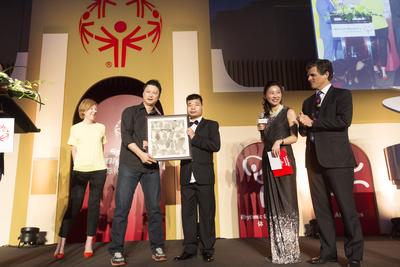 2015国际特殊奥林匹克融合慈善晚宴现场，来自浦东新区辅读学校的特奥运动员冯斌向中国著名青年艺术家贾蔼力先生赠画。