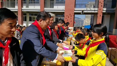 昭通市、鲁甸县、爱心企业爱茉莉太平洋中国等领导将捐赠的文具发给学生们
