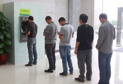 现场图：用户在邮储银行国产操作系统ATM前等待交易