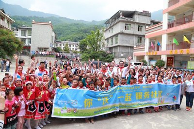 沃尔玛中国“你‘沃’一起 服务社区，20周年20小时志愿者活动”在北川邓家希望小学正式启动。图为沃尔玛员工志愿者与邓家希望小学学生在一起。