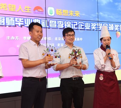 李锦记代表李学礼先生（中）和北京市劲松职高郭延峰校长（左一）接受希望厨师毕业纪念礼物