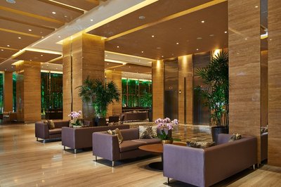 The expansive lobby is designed in warm tones framed against a screen of elegant bamboo