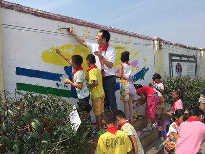 沃尔玛员工志愿者同逸夫完小的同学一起美化校园墙壁。