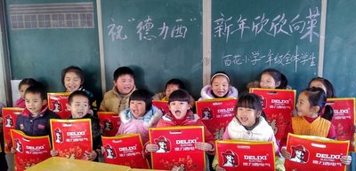 德力西电气芜湖湾沚希望小学的孩子们手拿德力西电气新春福袋，露出开心的笑容