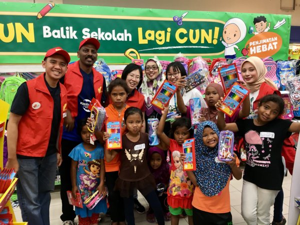 Murid-murid Malaysia, diiringi oleh sukarelawan dari Forest City, memilih dan membeli alat tulis