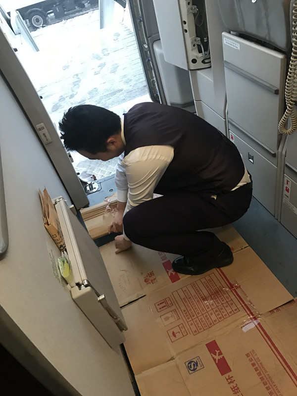 首都航空机组人员专门为旅客铺垫防滑纸板
