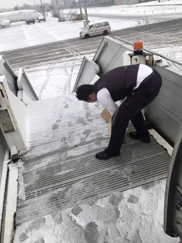 首都航空机组人员细心地进行客梯车铲雪除冰工作