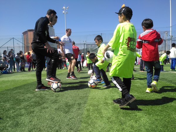 Jens Nowotny（左三）和一名勒沃库森球队教练（左一）在活动中向小朋友传授足球技巧