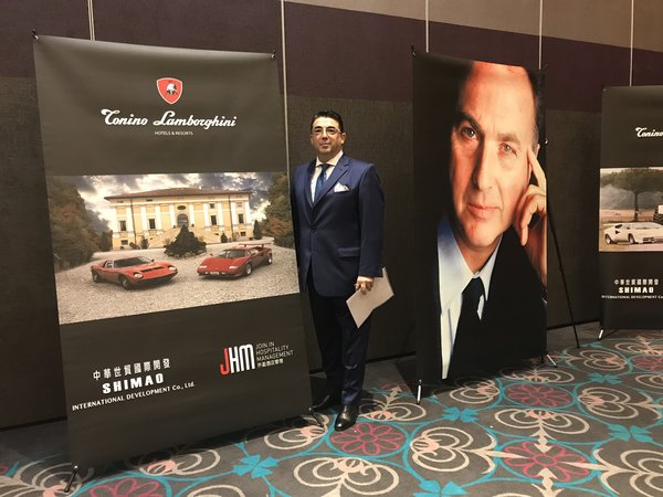 Roberto Simone (COO, Join.In Hospitality Management Co. Ltd.) posing next to Tonino Lamborghini posters during the signing ceremony