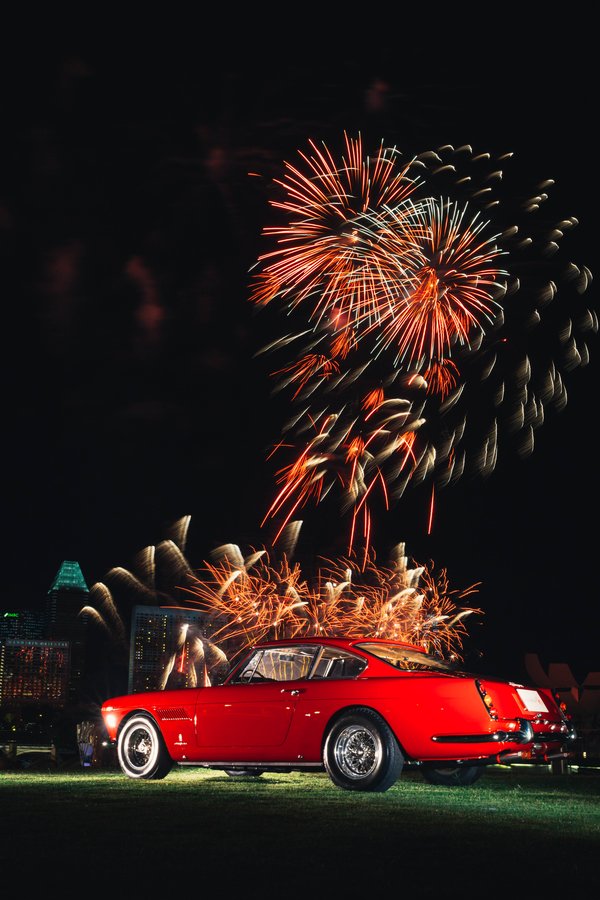 The 1962 Ferrari 250GTE against the panoramic waterfront with fireworks
