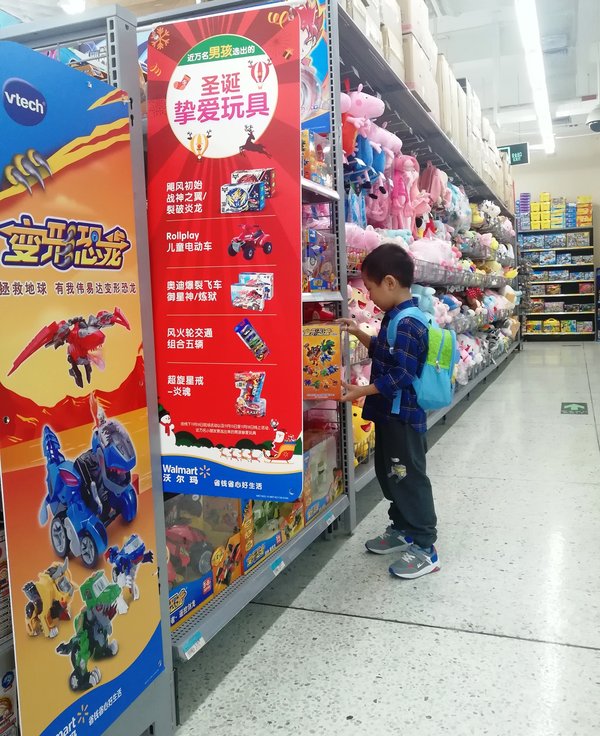 小朋友在沃尔玛玩具货架挑选“圣诞挚爱玩具”