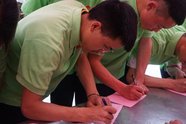 高二李锦记希望厨师李建峰（左）、李裕祥为甘孜州孩子写下爱心纸条