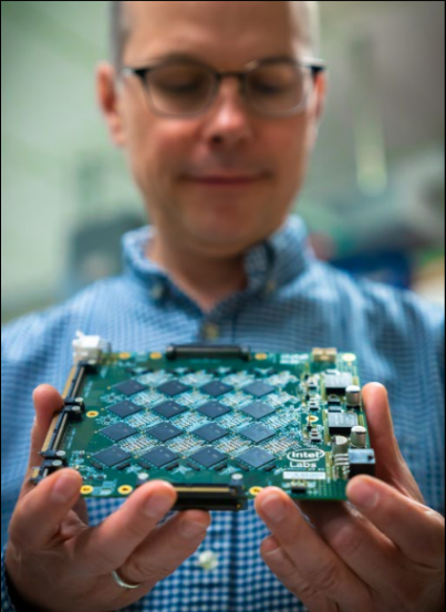 英特尔研究院院长Rich Uhlig手持一块英特尔Nahuku基板，每块基板包含8到32块英特尔Loihi神经拟态芯片。英特尔最新的神经拟态系统Pohoiki Beach由多块Nahuku基板组成，含64块Loihi芯片。