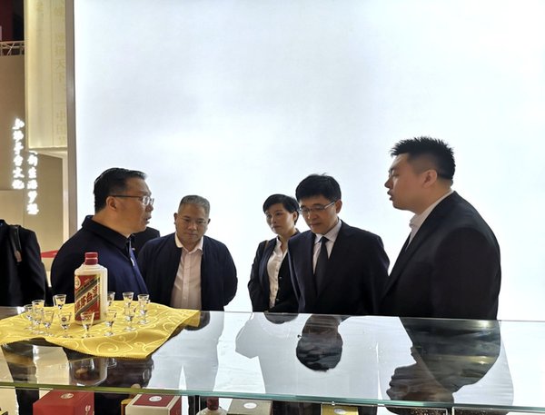 Moutai 회장 Li Baofang (왼쪽에서 첫 번째)과 Moutai 사장 Li Jingren(오른쪽에서 두 번째)이 Moutai 전시 부스를 찾아 제품에 관한 더 자세한 설명을 듣고 있다.