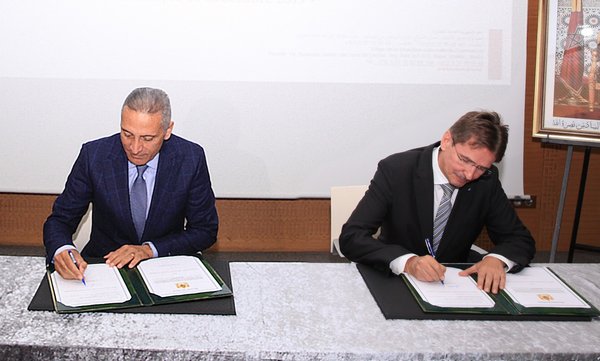 On the left H.E. Moulay Hafid Elalamy (The Minister of Industry, Trade, Green and Digital Economy) and the right Mr. Andreas Hofer (Regional Executive Vice President India, Middle East, Africa & Asia Pacific at TUV Rheinland) during signing the contract.
