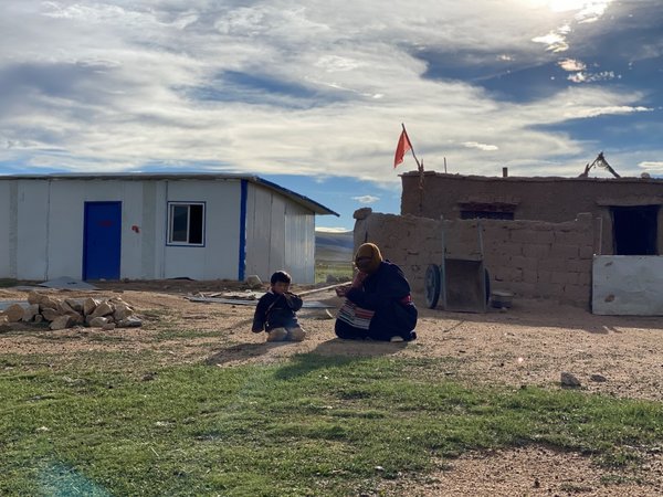 地元遊牧民の伝統的住居であるチベットの黒いテントの前に座る2人の地元住民